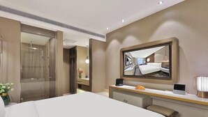 A hotel room with a large bed, a desk with a computer, a mirror, and a shower area. - Orange Hotel Shanghai Longbai New Village Subway Station (Shanghai)