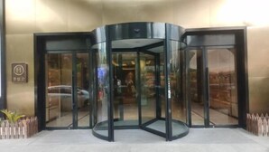 A revolving door entrance to a building with a sign that reads "Hotel." - Orange Hotel Shanghai Longbai New Village Subway Station (Shanghai)