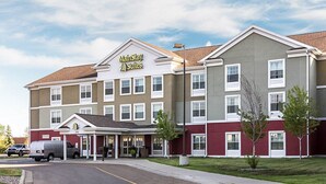 Un hotel MainStay Suites con un edificio de dos pisos, un acceso cubierto y un área de estacionamiento.