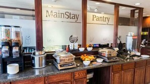 Un Pantry MainStay con máquinas de café de servicio propio, dispensadores de comida y una mesa de buffet.