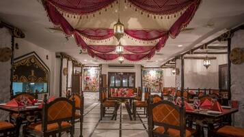 Un restaurante con decoraciones ornamentales en el techo, muebles de madera tradicionales y suelo de baldosas.