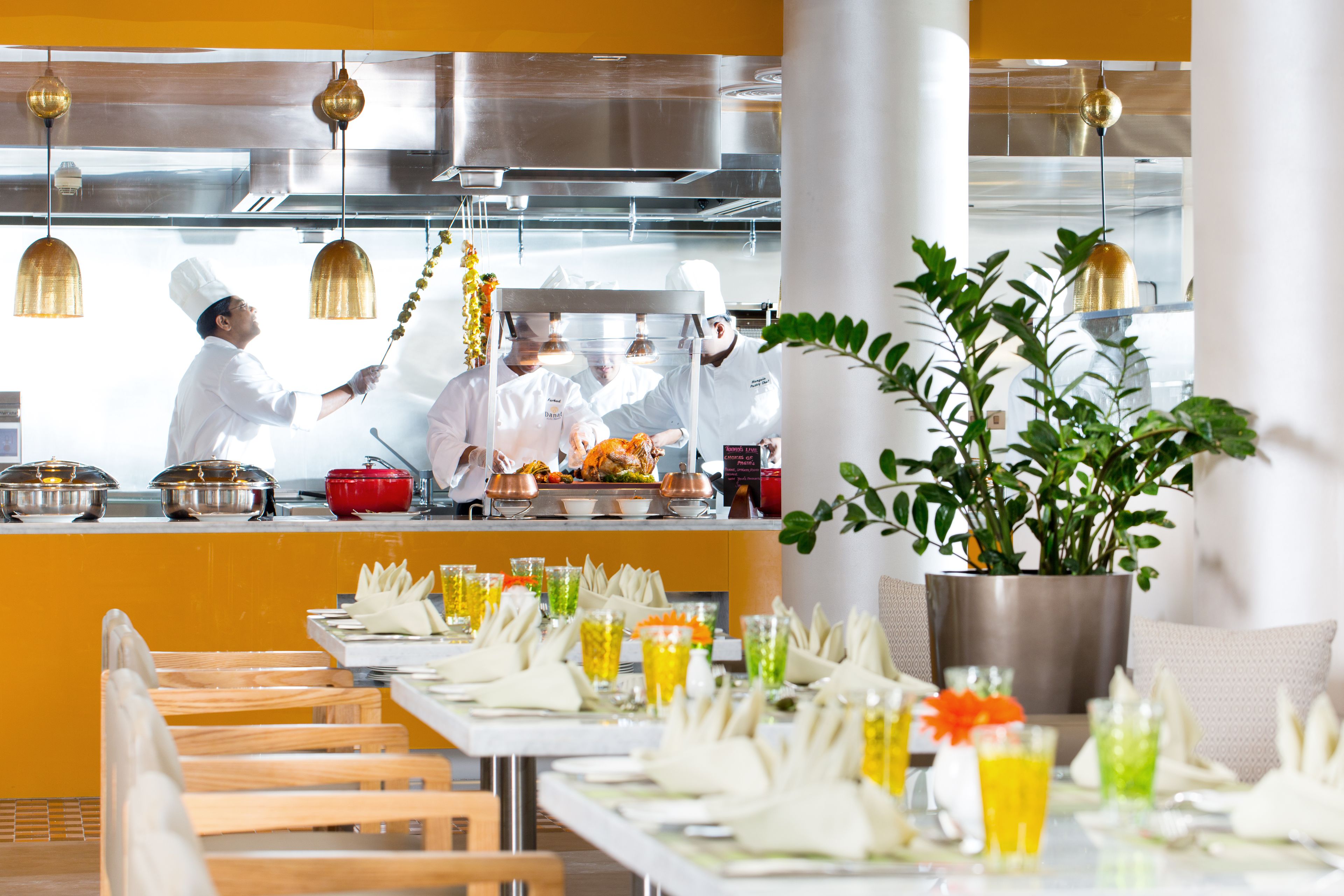 A restaurant with a long dining table, multiple chairs, and a chef preparing food.