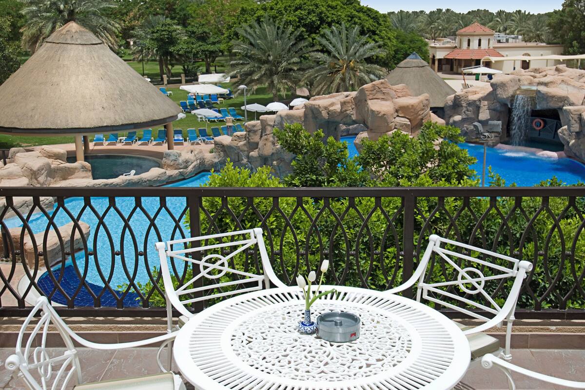 A pool area with a thatched-roof structure, lounge chairs, and a waterfall feature.