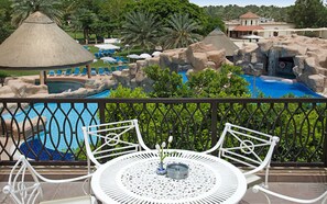 A pool area with a thatched-roof structure, lounge chairs, and a waterfall feature. - Danat Al Ain Resort (Al Ain)