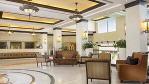 Un hall espacioso con techos altos, candelabros ornamentales y cómodas zonas de estar.
