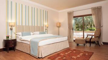 Une chambre d’hôtel avec un grand lit, une table de chevet, une chaise, une fenêtre avec des rideaux et une vue sur la verdure.