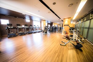 A gym with treadmills, weight machines, and a wooden floor.