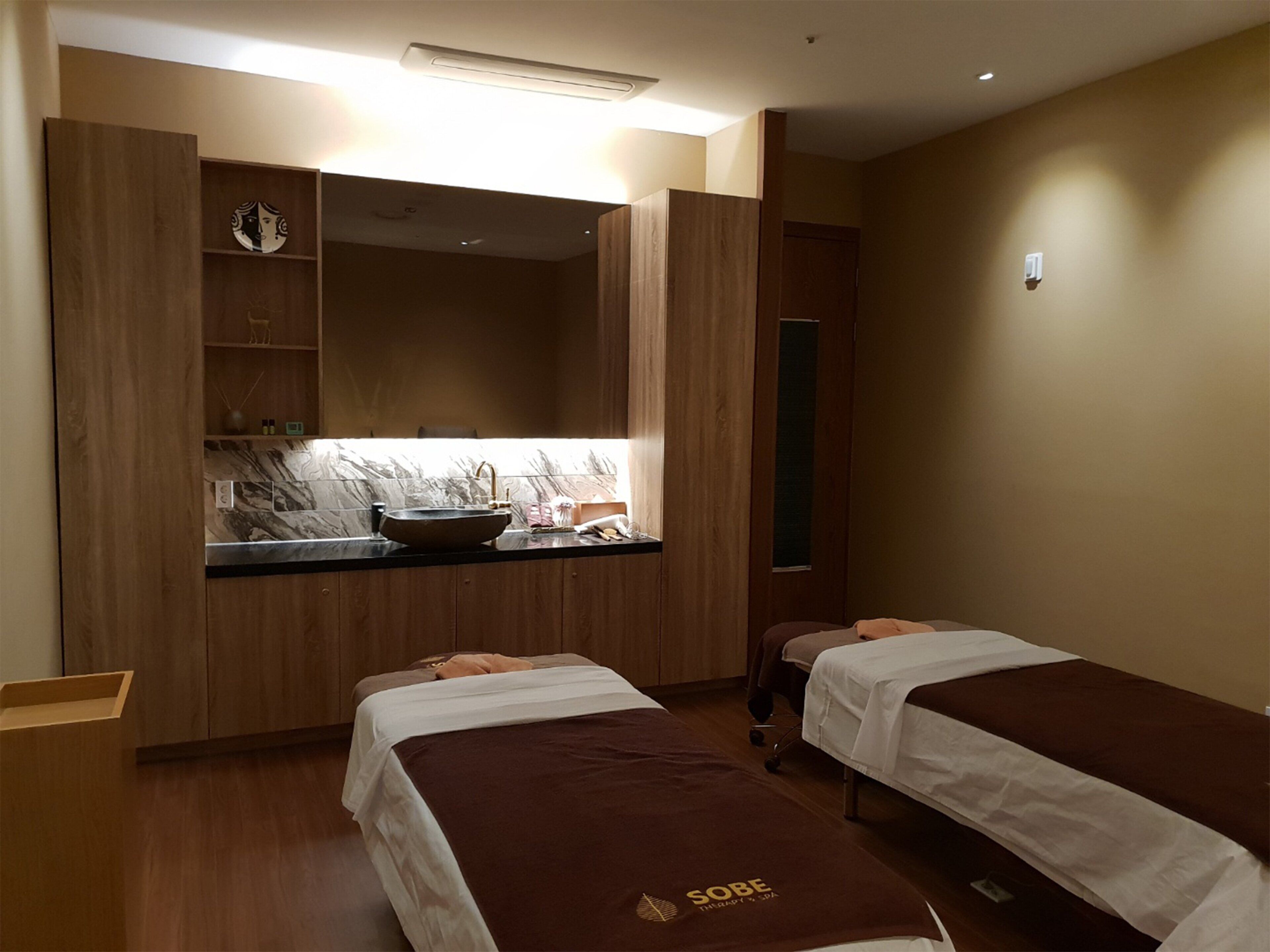 A hotel room with two beds, a bathroom with a sink, and a small seating area.