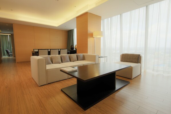 Een moderne hotelkamer met een hoekbank, een kleine bank, een salontafel en een vloerlamp.