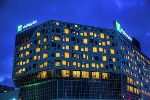A hotel with a modern design, featuring a grid of windows and a prominent signage at the top.