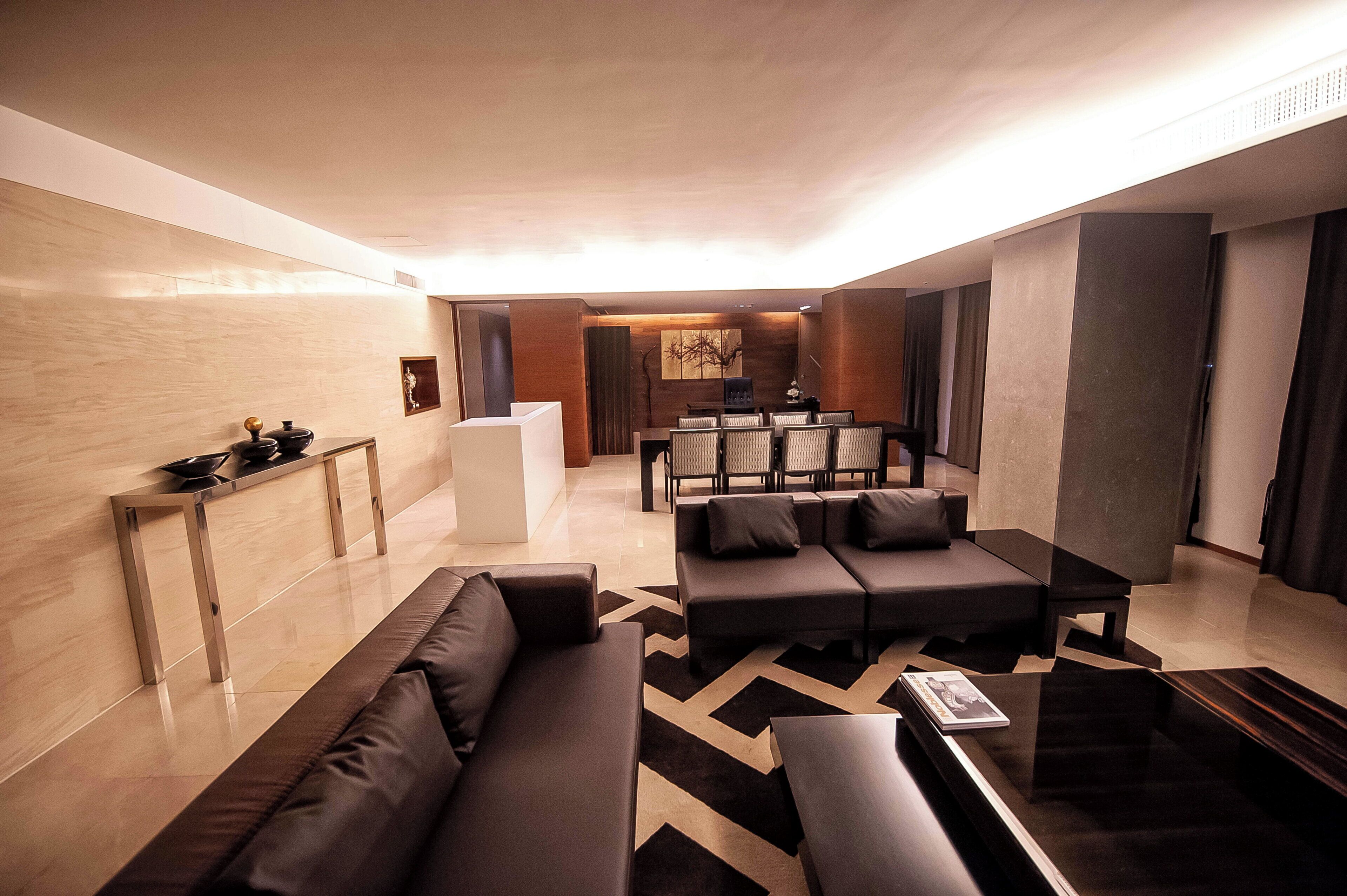 A modern living room with a sofa set, a coffee table, and a dining area with chairs and a table.
