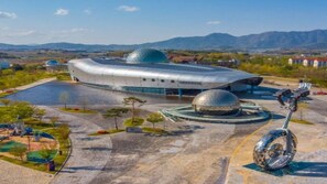 Un edificio futurista con una estructura en forma de cúpula y una plaza circular con una escultura.