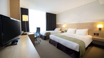 A hotel room with a TV, two beds, a desk, and a chair.