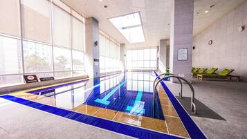 An indoor swimming pool with clear water, a no diving sign, and a clock on the wall.