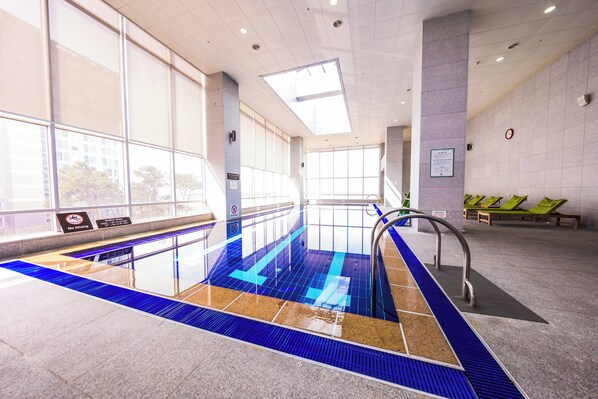 An indoor swimming pool with clear water, a no diving sign, and a clock on the wall.