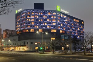 A Holiday Inn hotel with a modern design, featuring a grid of illuminated windows and a prominent green logo.