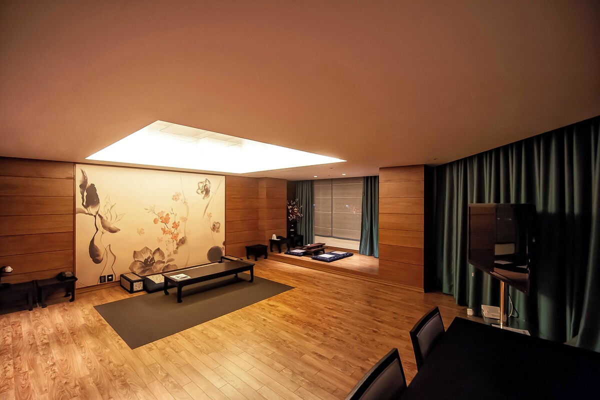 Una sala de estar moderna con suelo de madera, un televisor de pantalla plana, un sofá, una mesa de centro y un cuadro en la pared.