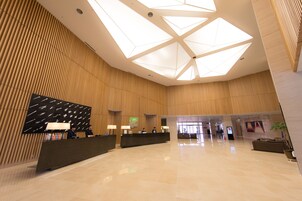 A spacious lobby with a high ceiling, a reception desk, and a modern design.
