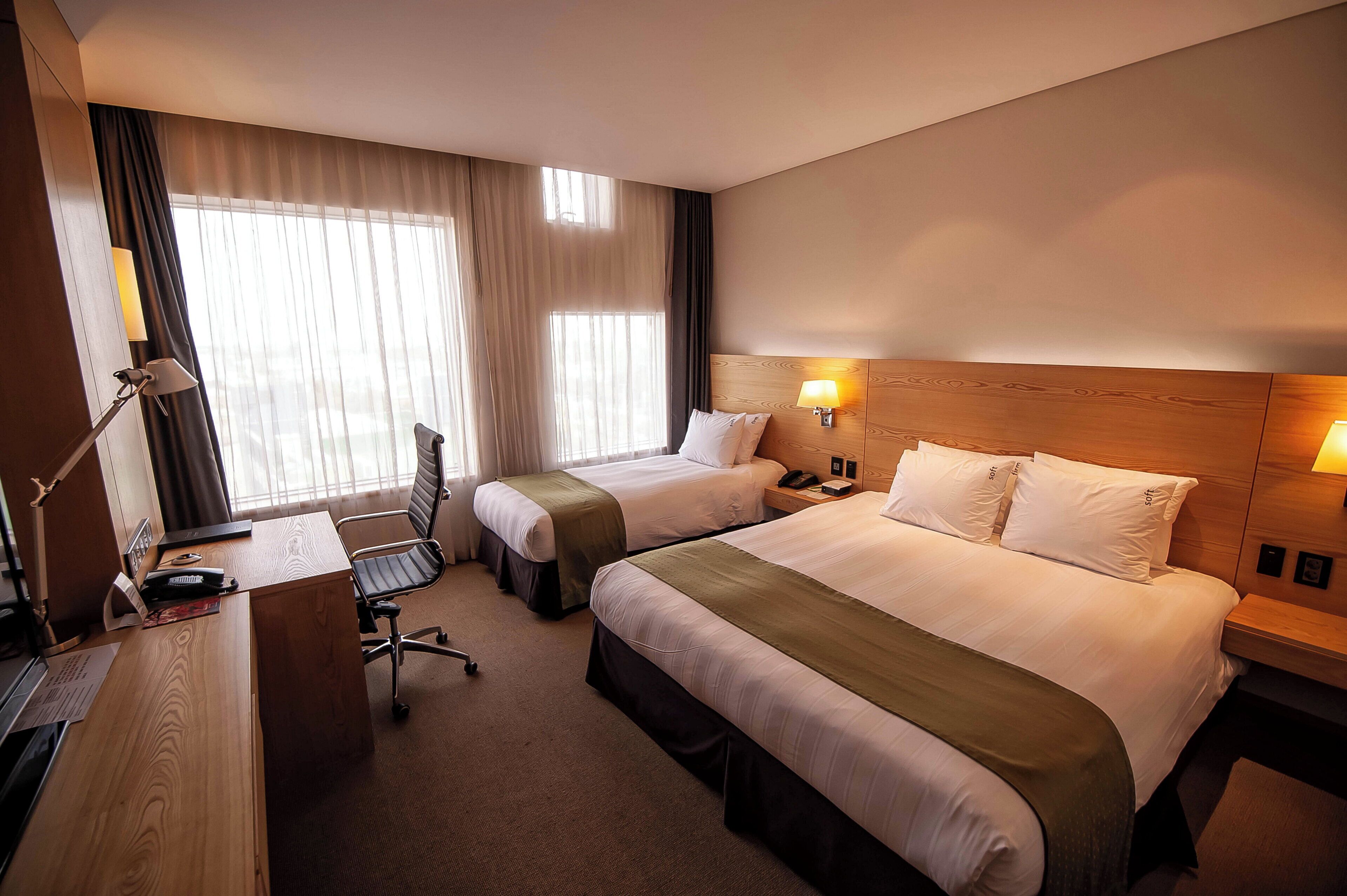 Een hotelkamer met twee bedden, een bureau, een stoel en een lamp.