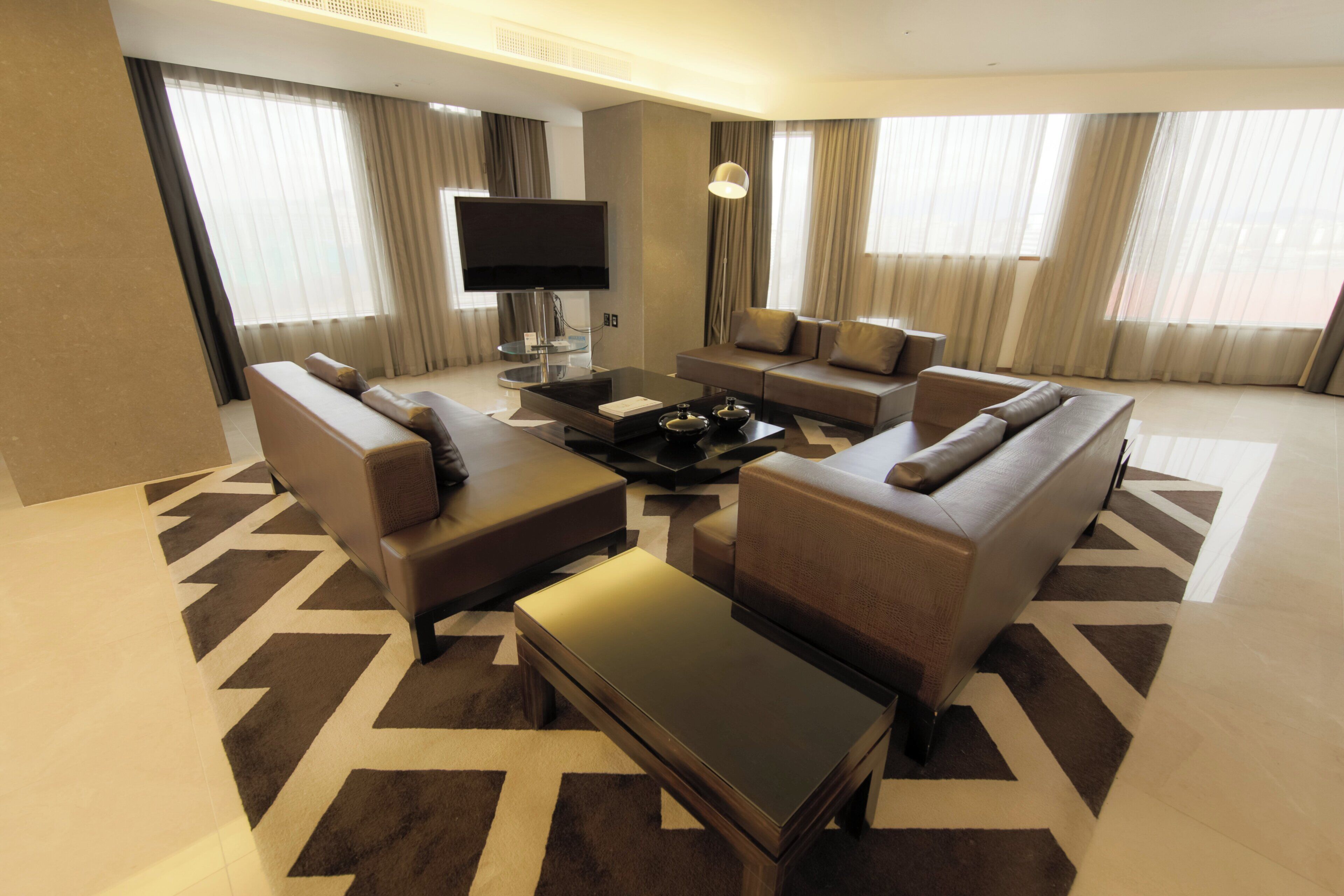 A modern hotel living room with a sofa set, a coffee table, and a flat-screen TV.