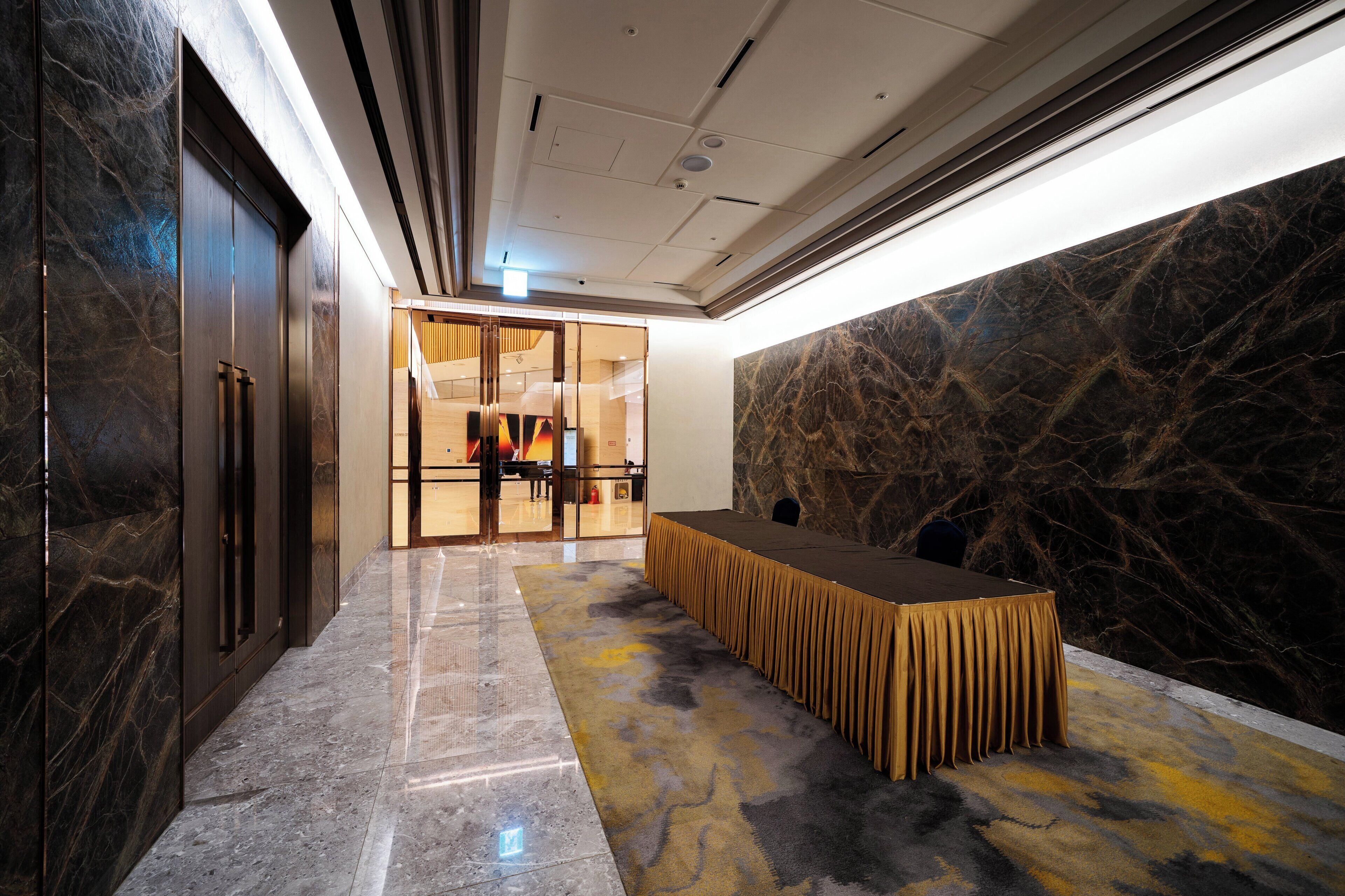 A modern interior with a marble floor, a reception desk, and a glass door leading to a reception area.