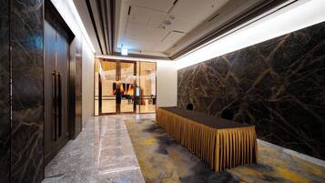 A modern interior with a marble floor, a reception desk, and a glass door leading to a reception area.