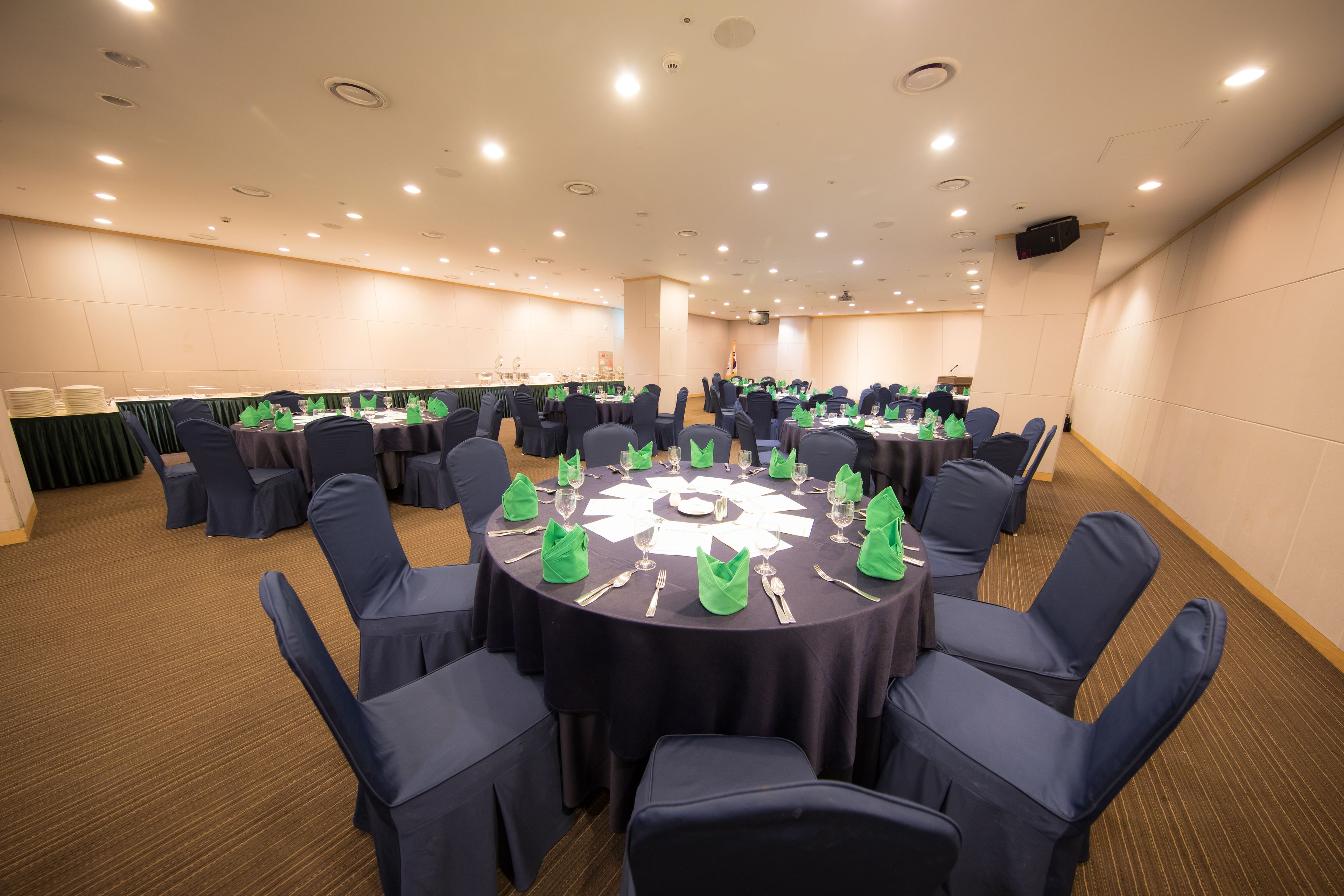 Une salle de conférence équipée de tables rondes, de chaises et d’une estrade.