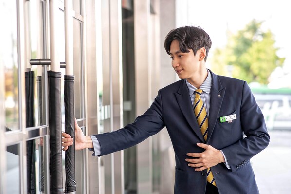 A man in a suit leaning against a glass door with a name tag.