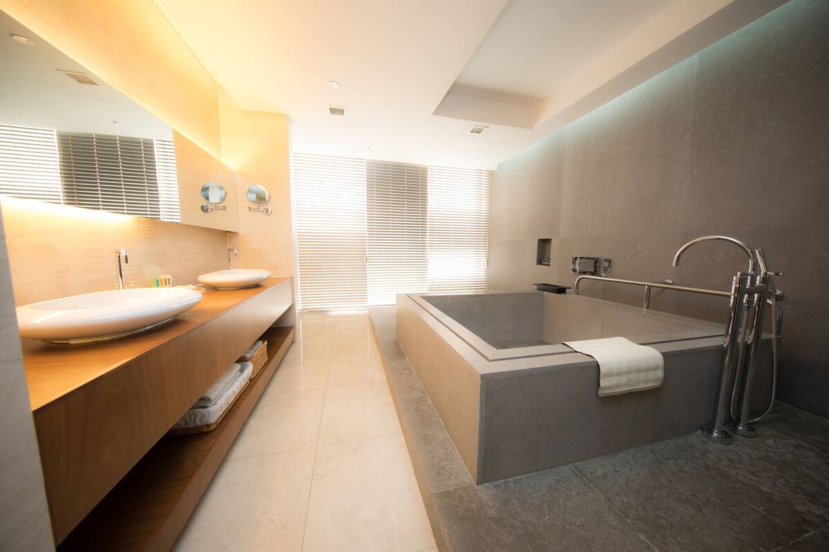 A modern bathroom with a large bathtub, two sinks, and a vanity with a mirror.