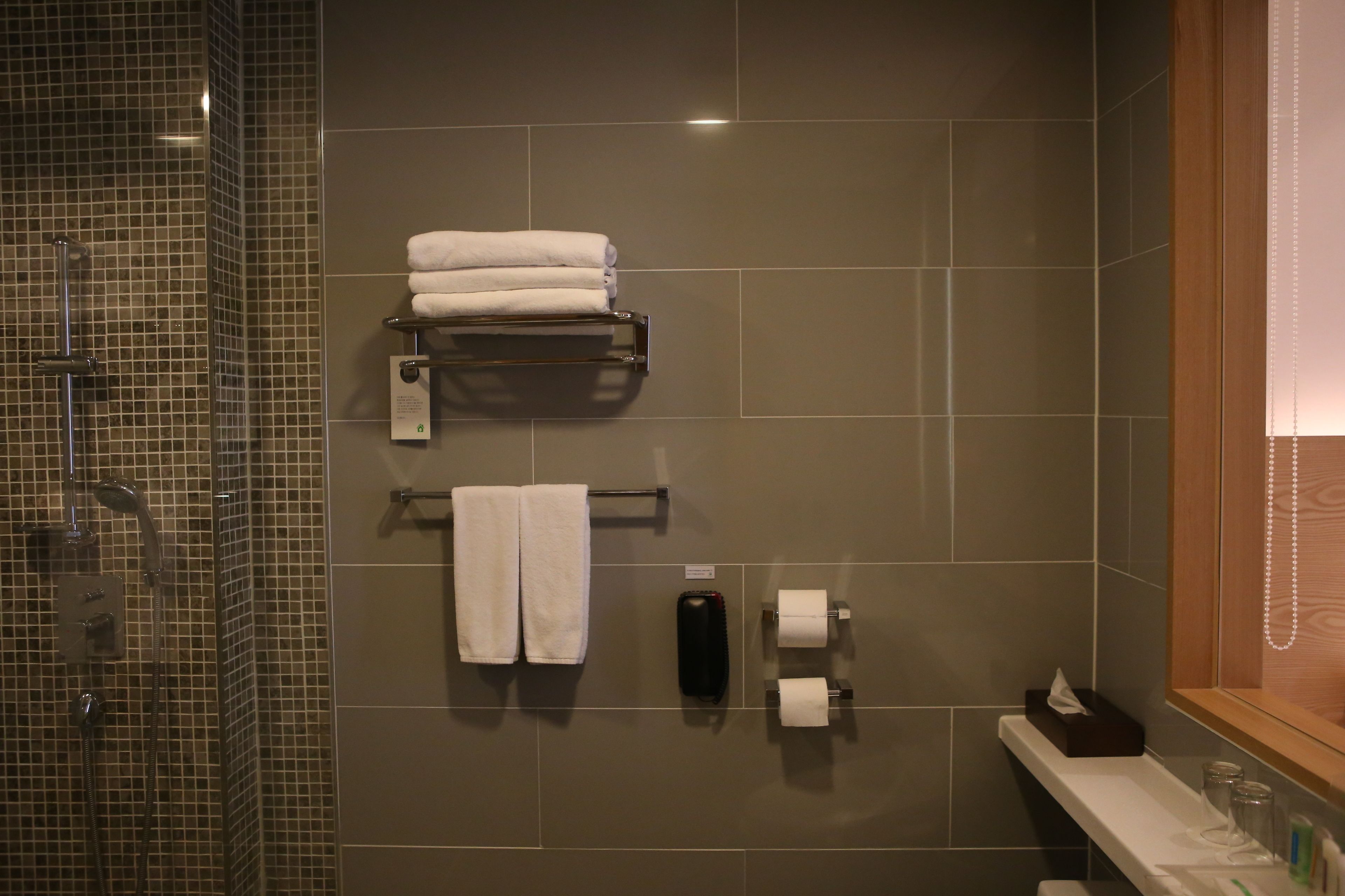Une salle de bain avec une douche à parois de verre, un porte-serviettes avec des serviettes pliées, un distributeur de savon et un porte-rouleau de papier toilette.