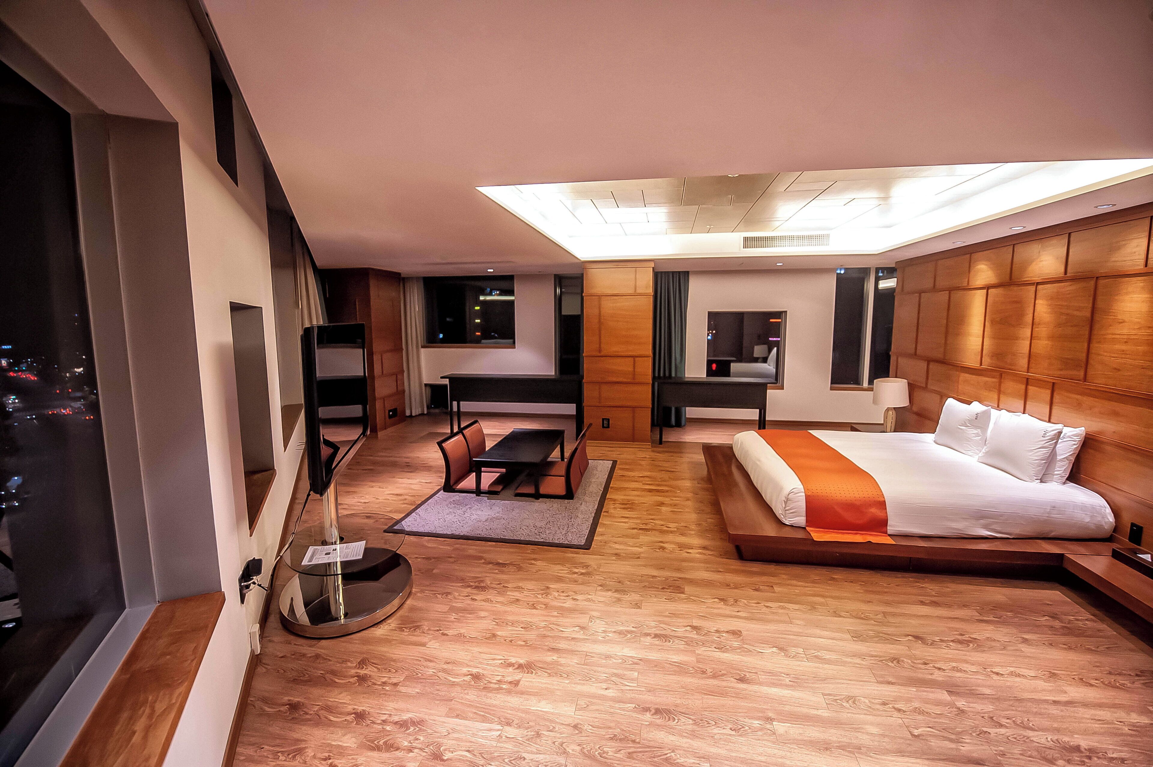A modern hotel room with a large bed, a desk, and a seating area.