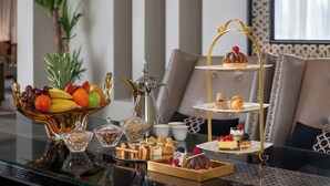 A dining table with a fruit bowl, a coffee pot, and a tiered dessert stand. - Sofitel Shahd Al Madinah (Madinah)