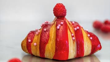 Postre amb una frambuesa a dalt, envoltat de petits punts rosats.