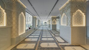 A corridor with intricate wall carvings and a patterned carpet. - Sofitel Shahd Al Madinah (Madinah)