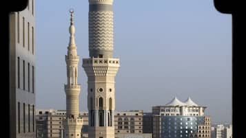 A tall minaret with intricate architectural details, surrounded by other buildings and domes.