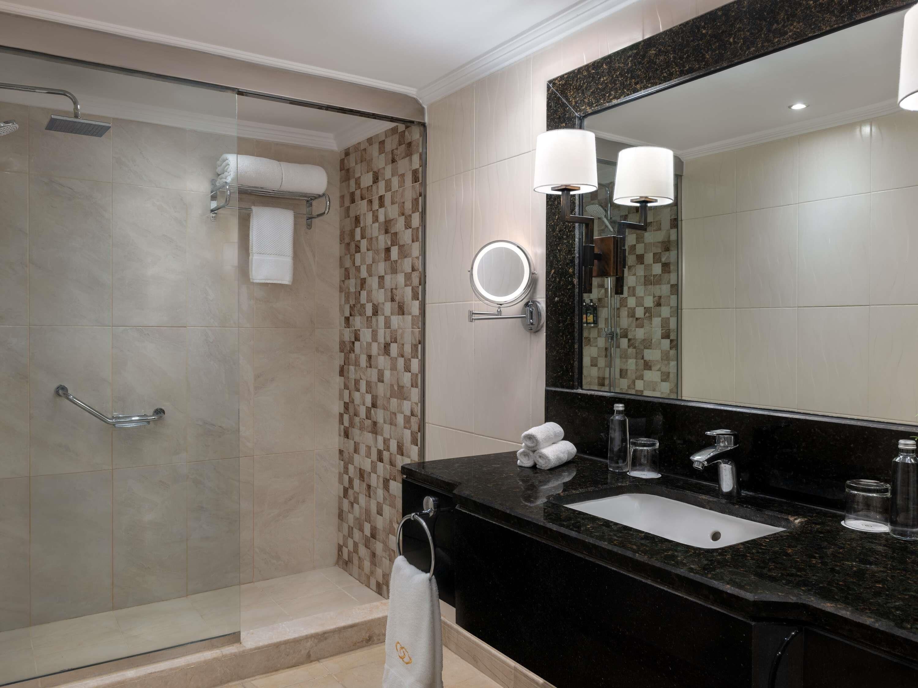 A modern bathroom with a glass shower, a vanity with a sink, and a large mirror.