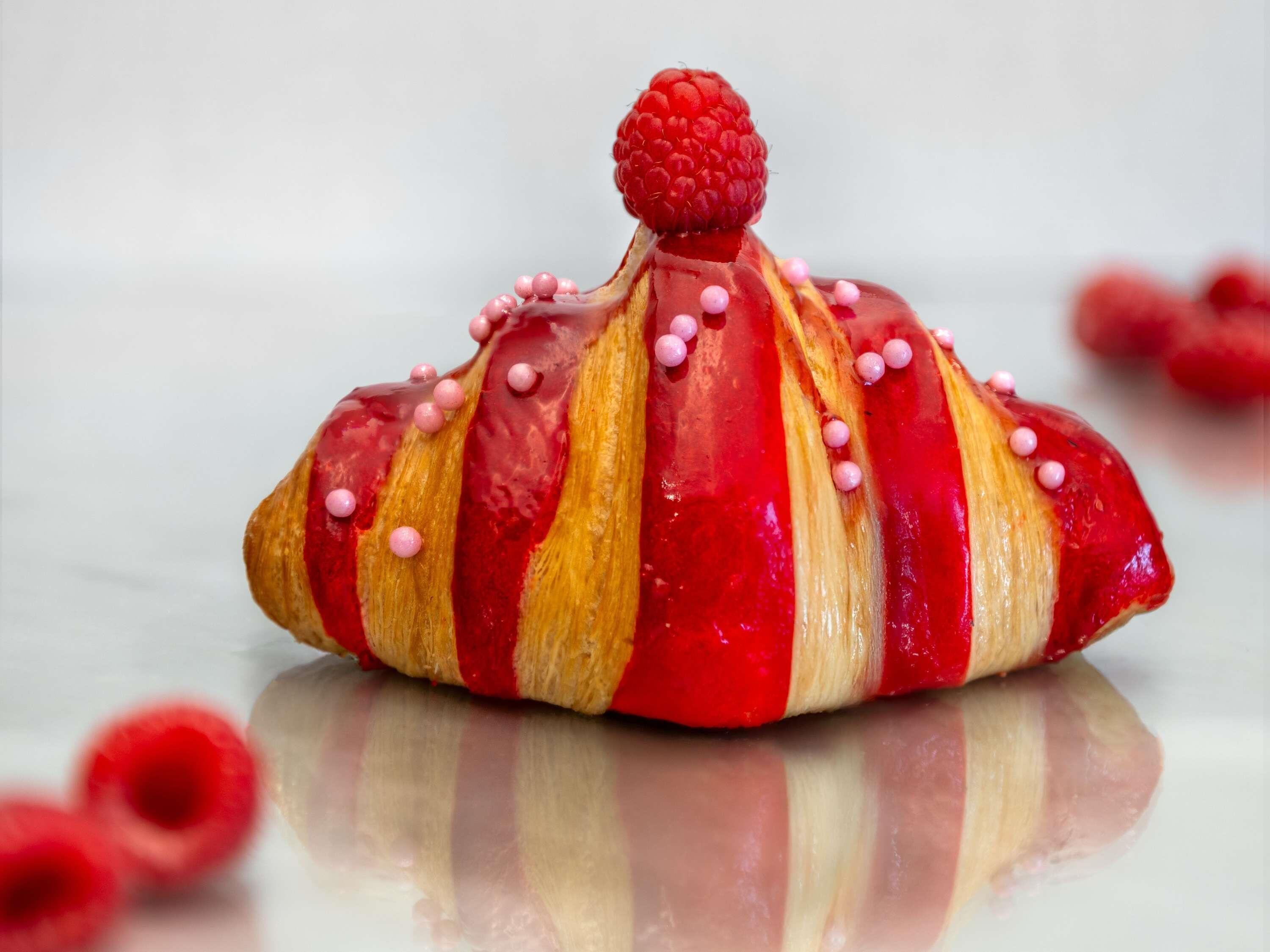 Un pastelito decorado con puntos rosados y una frambuesa encima.