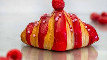 Un pastelito decorado con puntos rosados y una frambuesa encima.