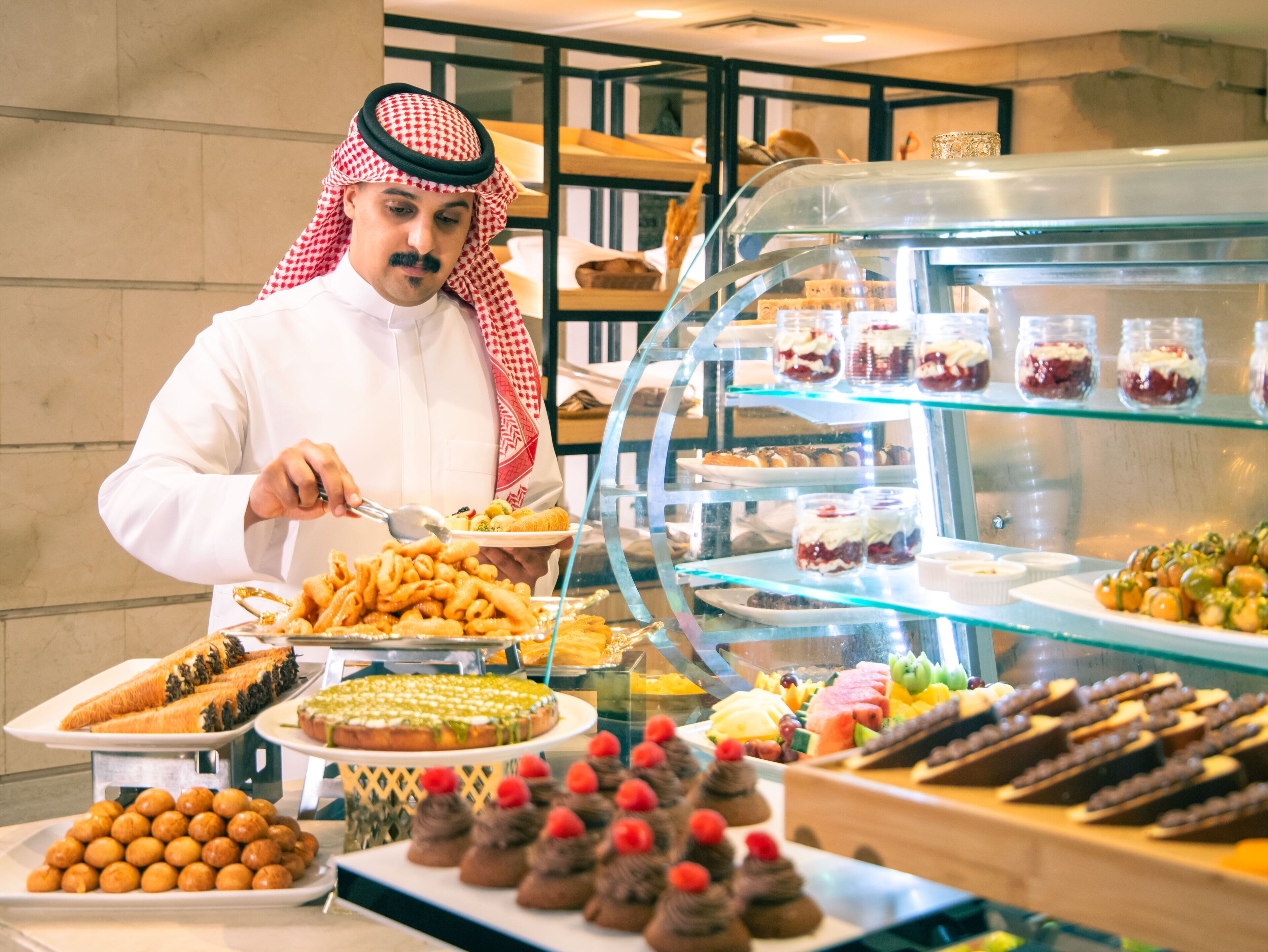 A buffet with various desserts and a person serving food.