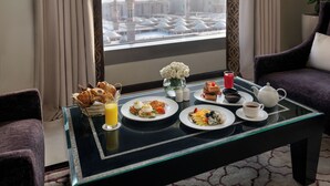 Una mesa de comedor con alimentos para el desayuno, vistas a una mezquita y una habitación moderna con mobiliario morado.