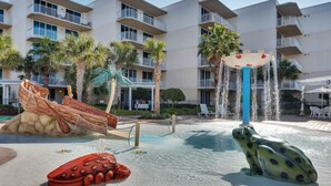 A water park area with a frog-shaped water feature, a boat-shaped play structure, and palm trees. - Waterscape Condominiums (Fort Walton Beach)