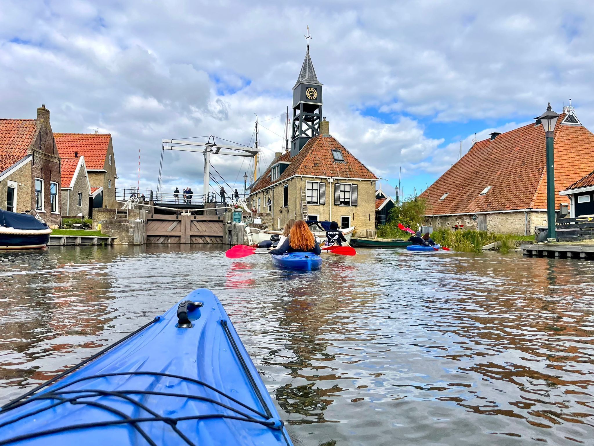 A canal scene with a boat, a clock tower, and traditional buildings.