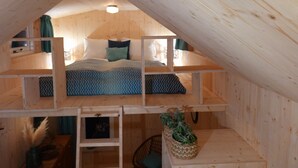 Un dormitorio tipo loft con literas, paredes de madera y un pequeño espacio de trabajo.