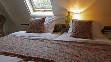Un dormitorio con tragaluces, ropa de cama estampada con flores y una lámpara de noche.