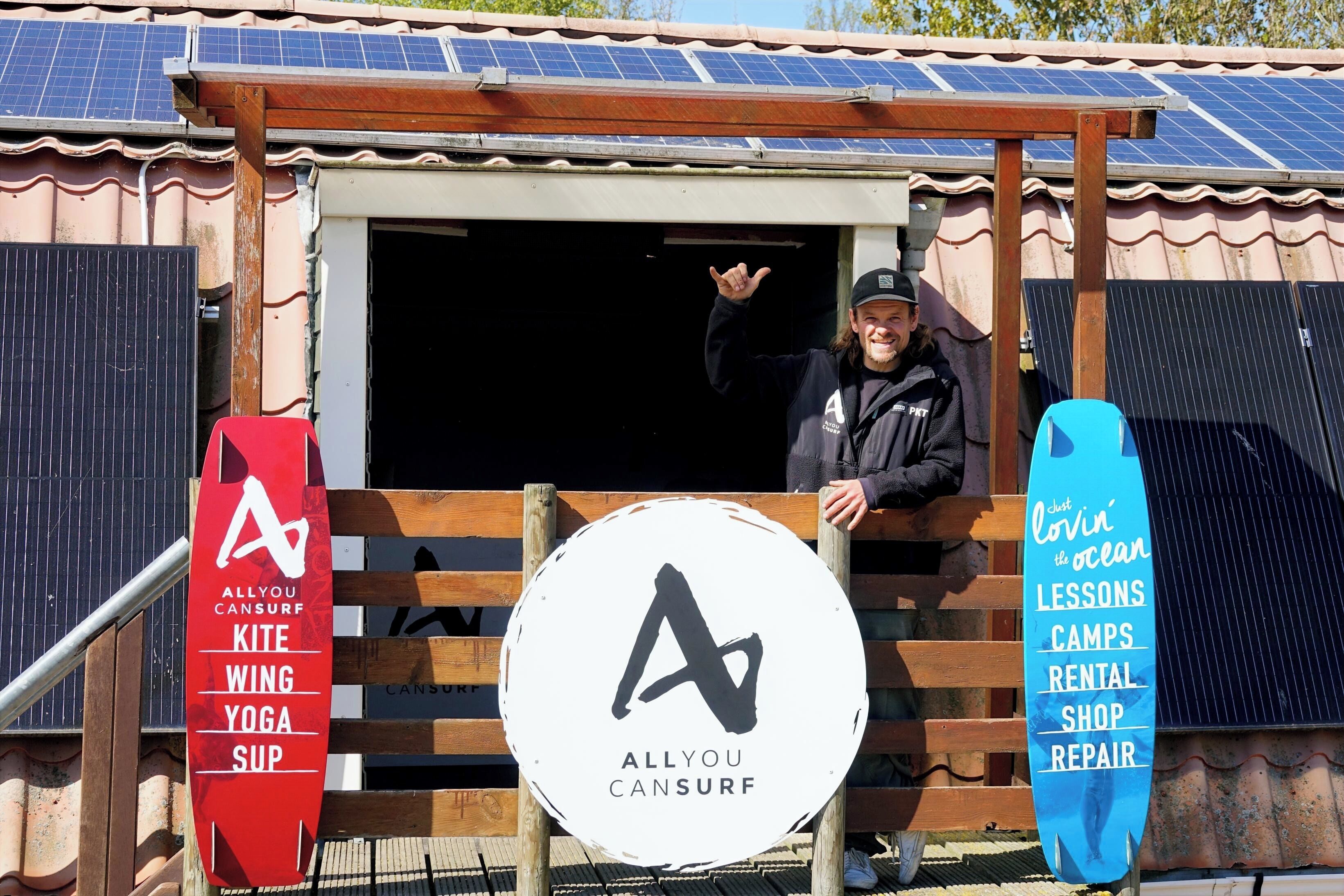 A building with a signboard for Allyou Cansurf, featuring activities like kite surfing, wing yoga, and SUP.