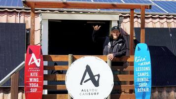 A building with a signboard for Allyou Cansurf, featuring activities like kite surfing, wing yoga, and SUP.