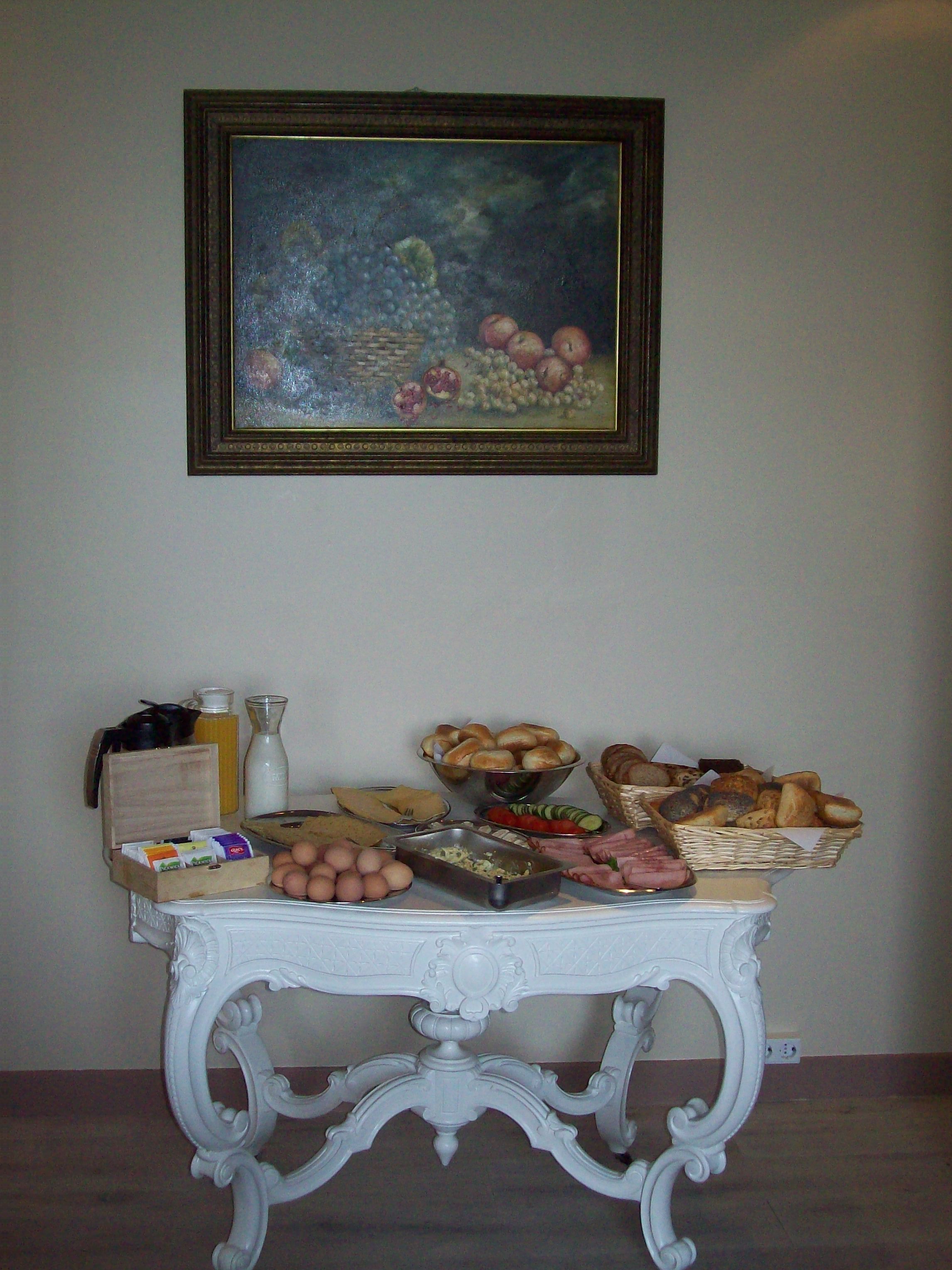 A dining table with various food items and a painting on the wall.