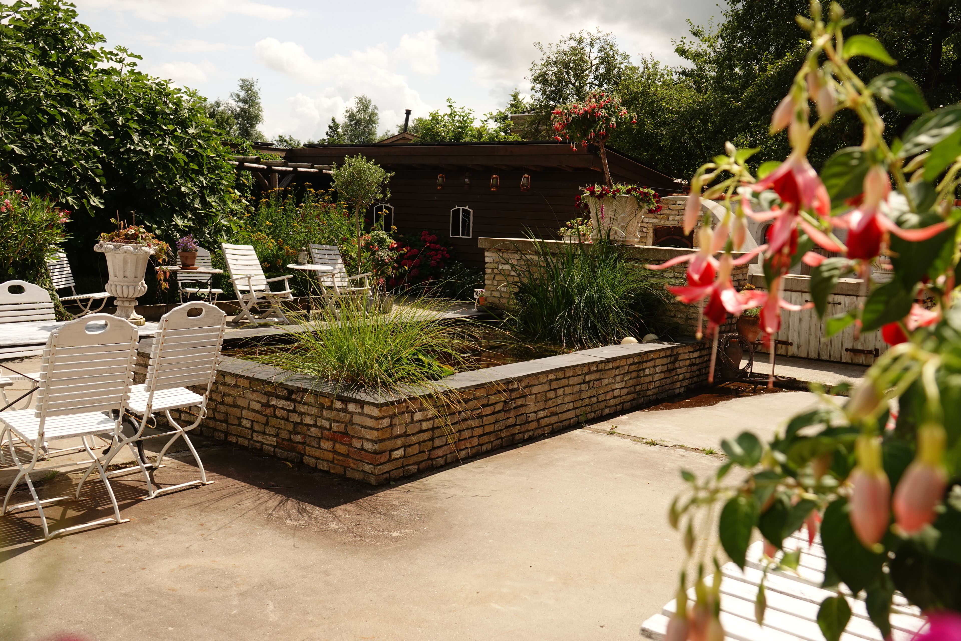 Un espace patio avec des sièges d’extérieur, un jardin en briques et une maison en arrière-plan.