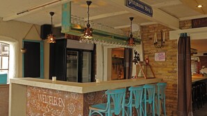 Una zona de bar con pared de pizarra, taburetes y luces colgantes.
