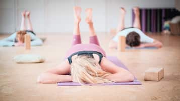 A yoga class in a room with wooden flooring, yoga mats, and blocks.